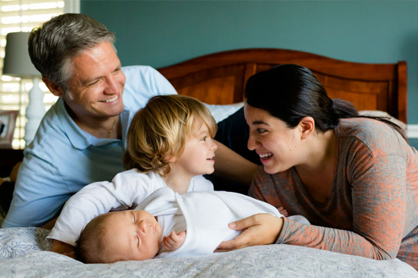 Photo of a two parents and their young kids smiling at home