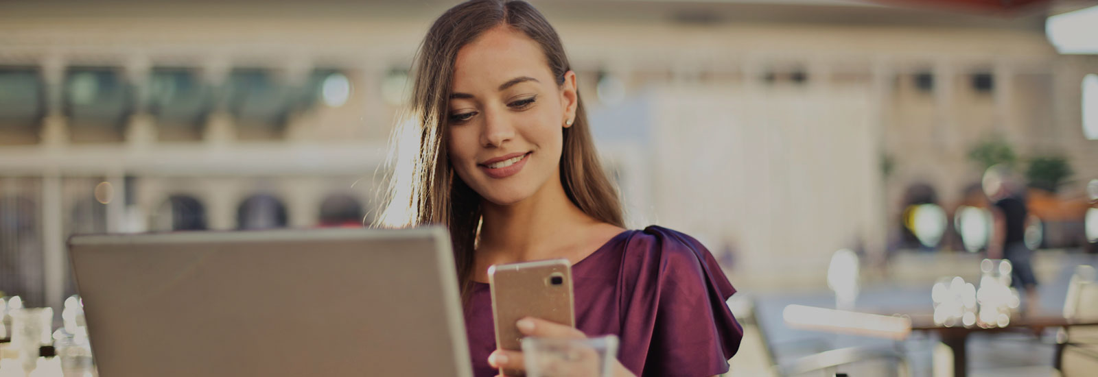 Photo of a woman using a cell phone and laptop