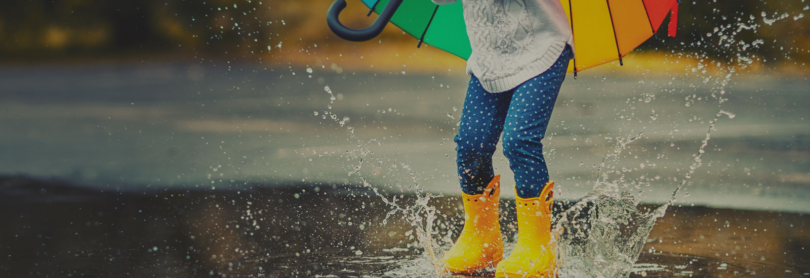 Photo of a child splashing in water in yellow rubber boots