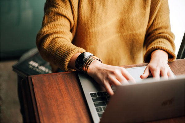 A young adult typing on their personal computer