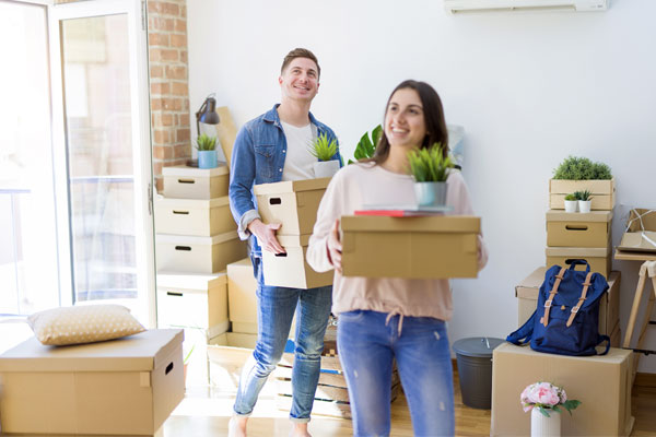 Photo of couple moving boxes into new home