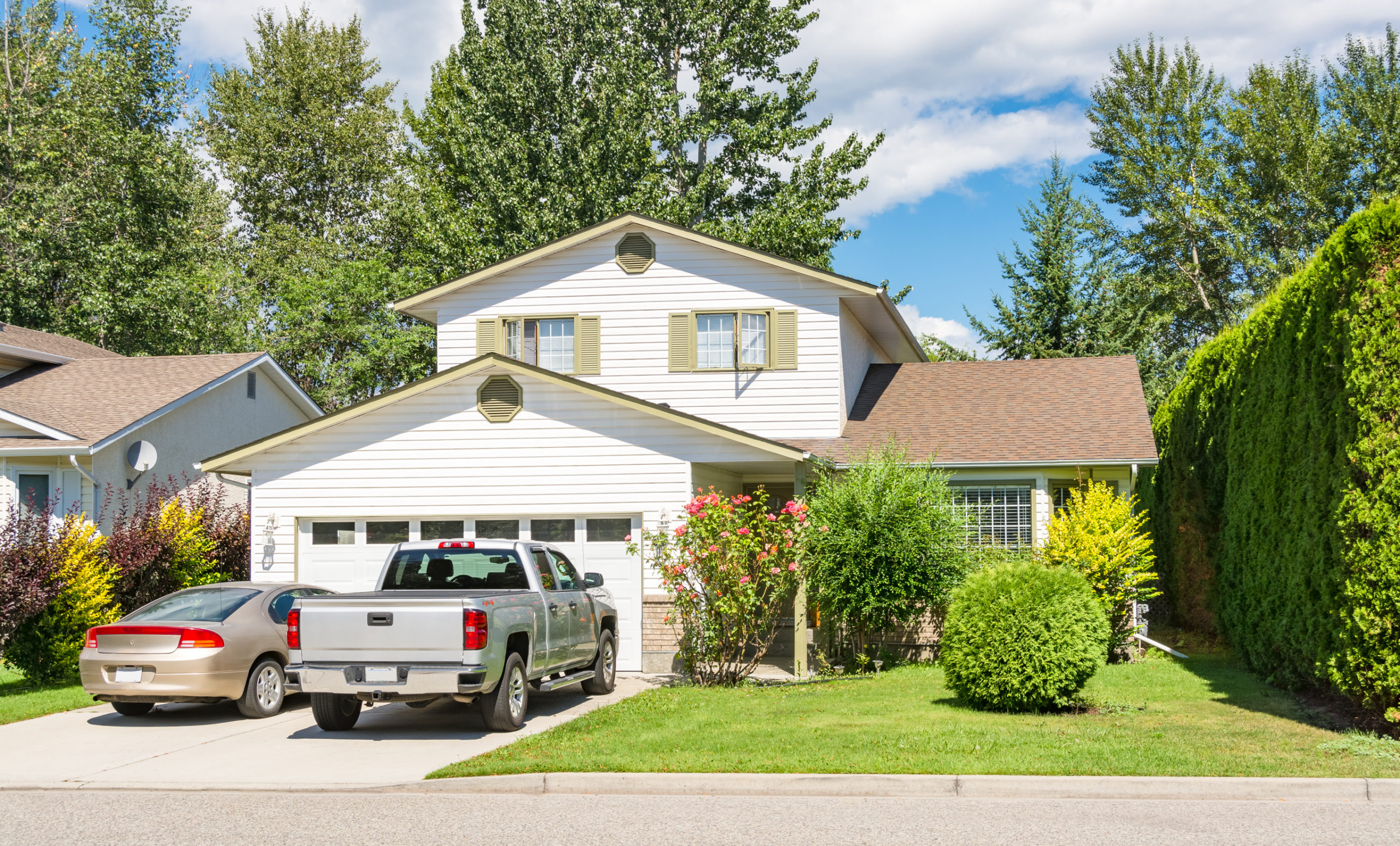 Photo of a home with manicured yard and silver truck in the driveway